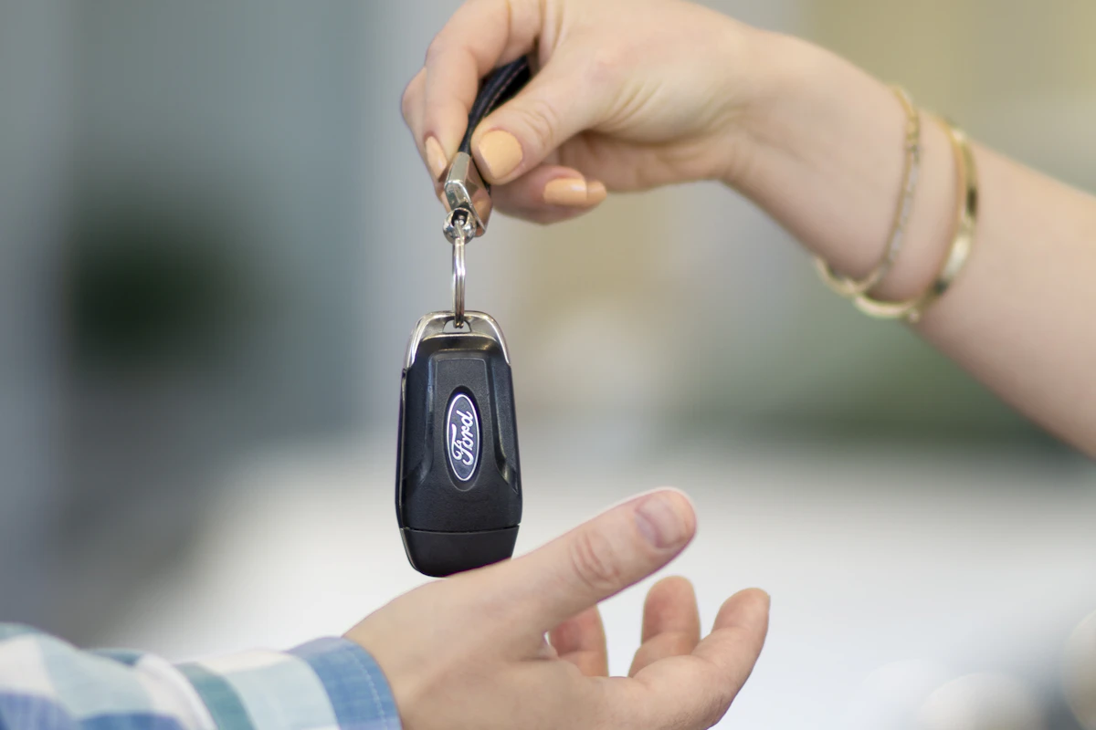 Vendedor de una compraventa entregando las llaves del coche a un cliente que lo encontró en el catálogo online